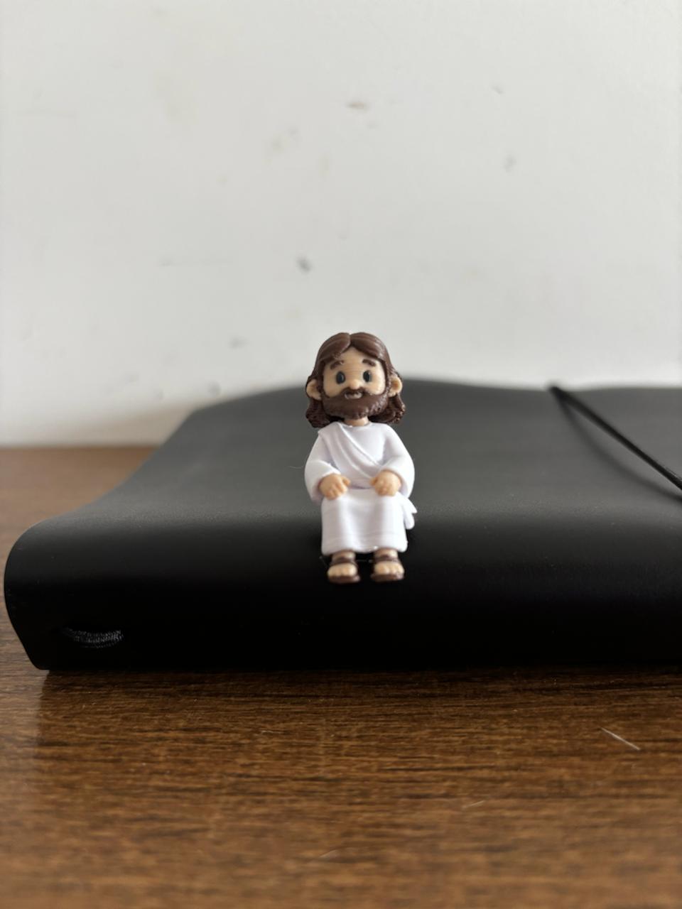 Mini Jesus sentado na borda de um objeto, foto real